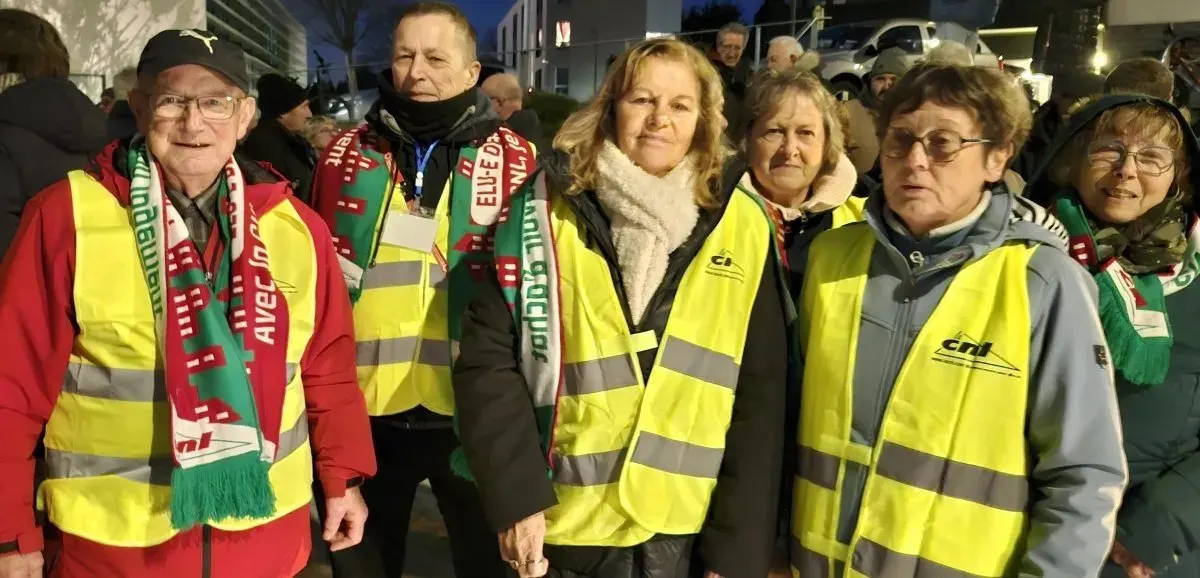 Militant·es et représentant·es CNL en gilets jaunes et écharpes rouges et vertes lors d'un rassemblement nocturne