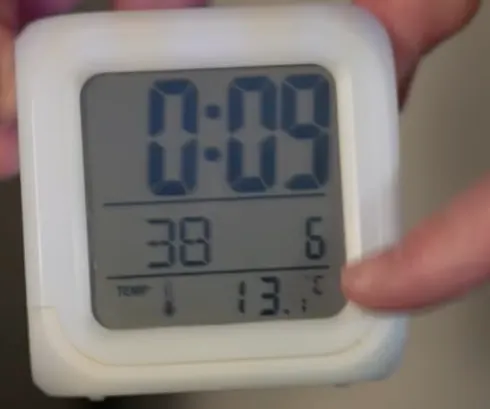 Photo d'un thermomètre d'intérieur affichant 13,1 °C tenu à la main dans un logement