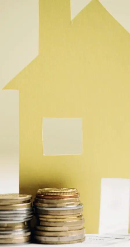 Piles de pièces de monnaie devant une maison en papier
